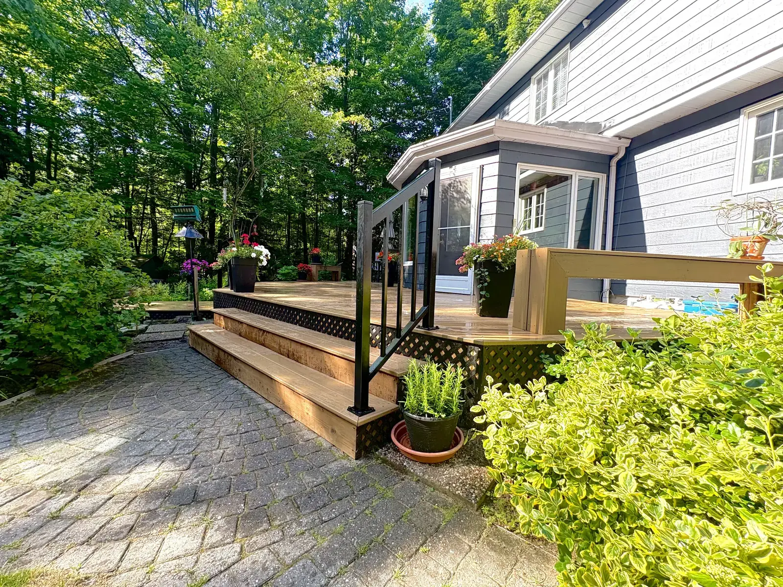 Aménagement paysager fini — terrasse, escalier en bois et allée en pavé uni