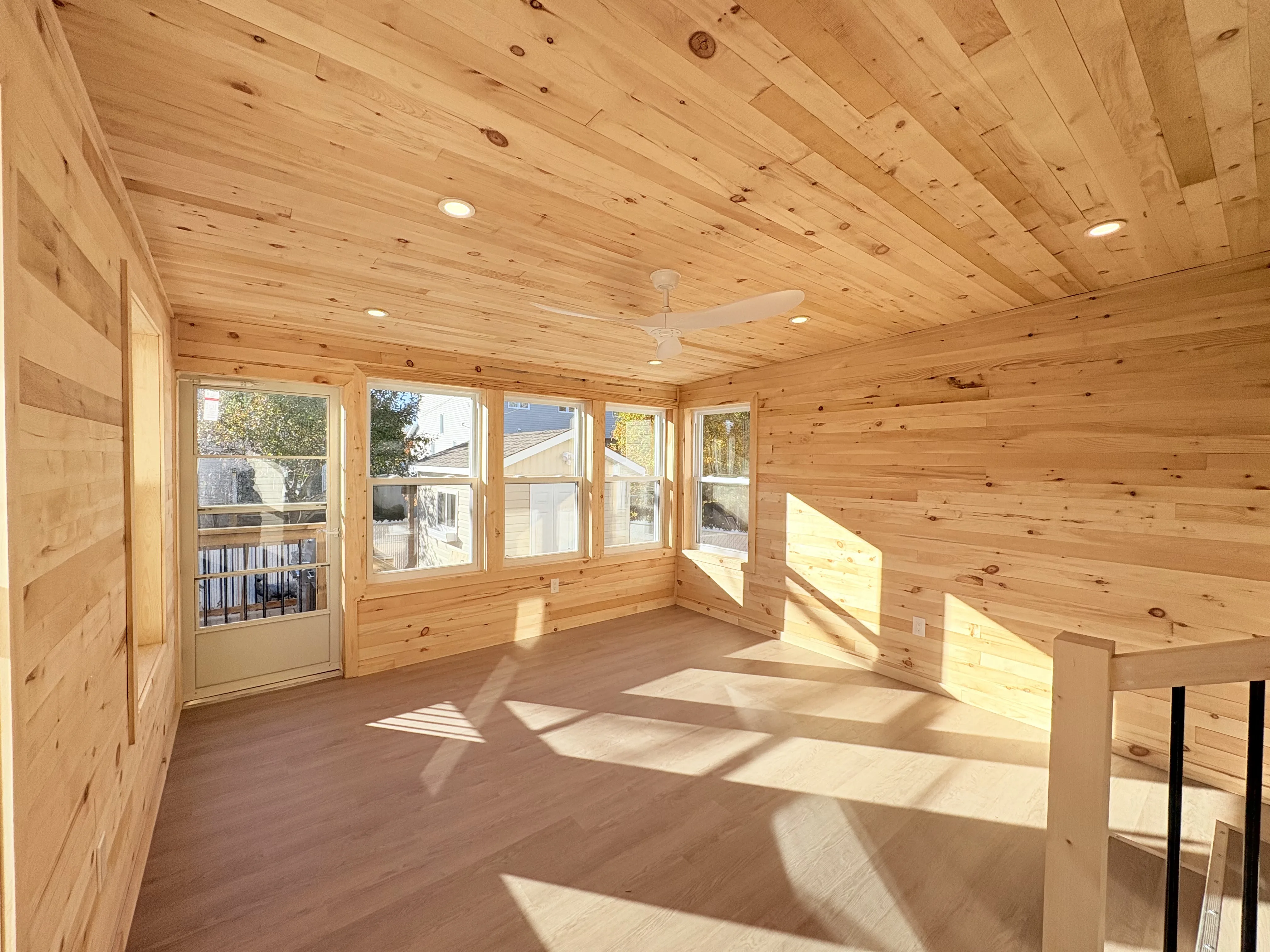 Espace de vie lambrissé de bois avec grandes fenêtres et plafond en bois